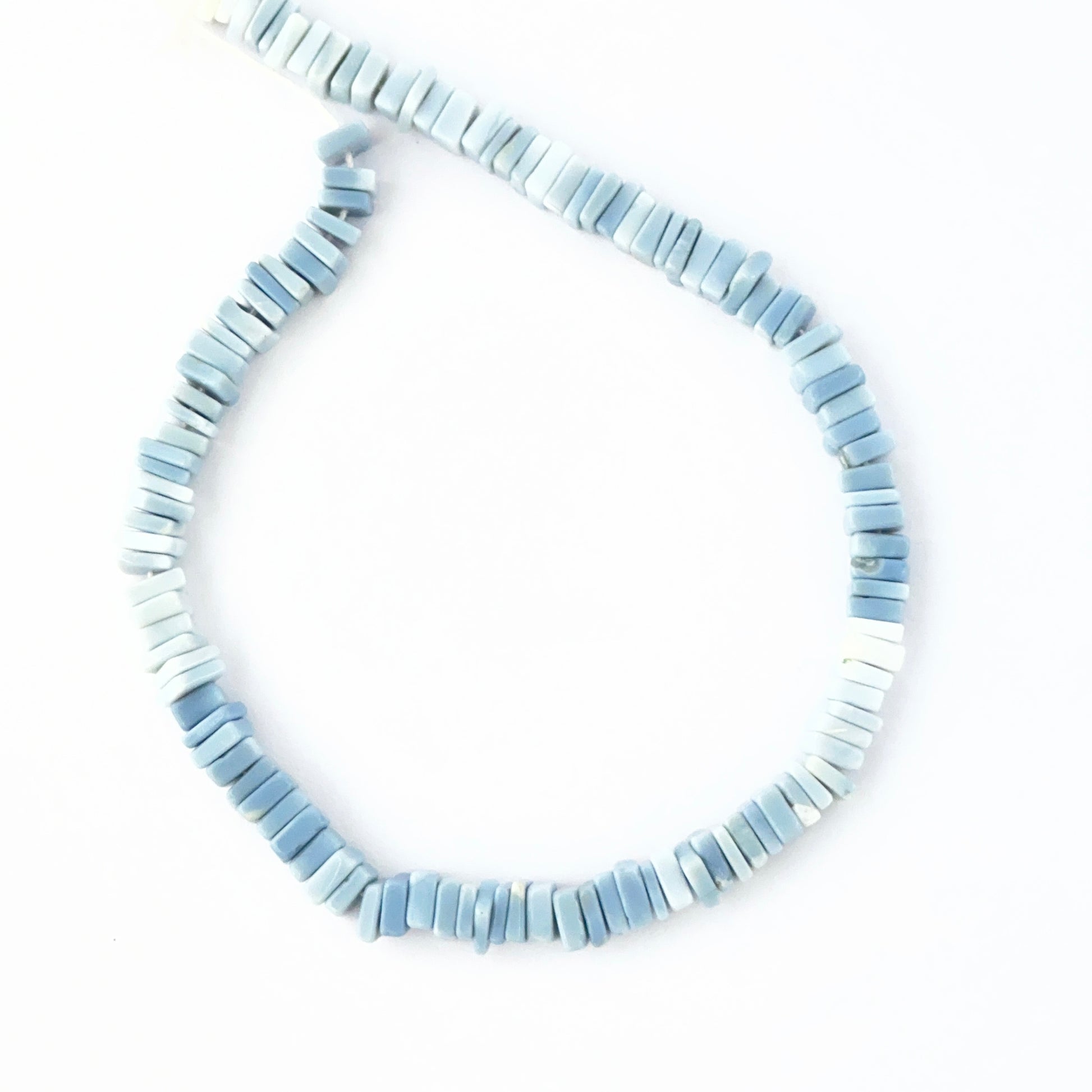 Close‑up of Denim Opal stone beads arranged in a strand with earthy patterning.