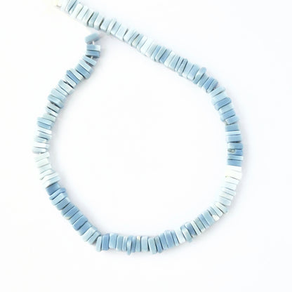 Close‑up of Denim Opal stone beads arranged in a strand with earthy patterning.