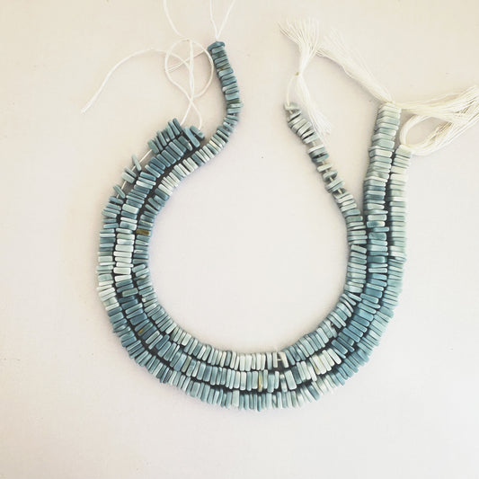 Light reflects off faceted Denim Opal beads, showcasing their semi-gloss finish.