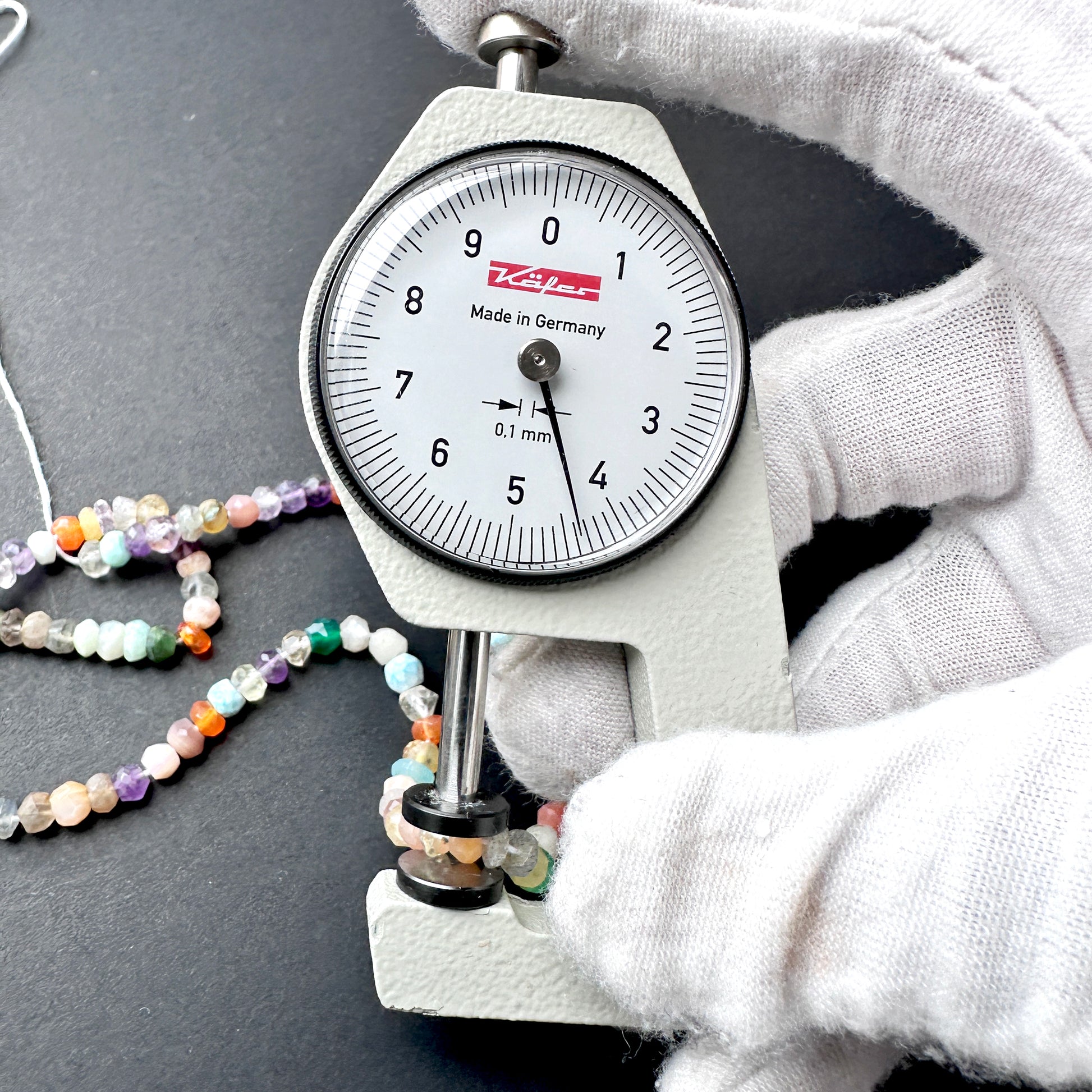 A dial gauge measures the Disco faceted rondelle 4.3-4.5mm gemstone.