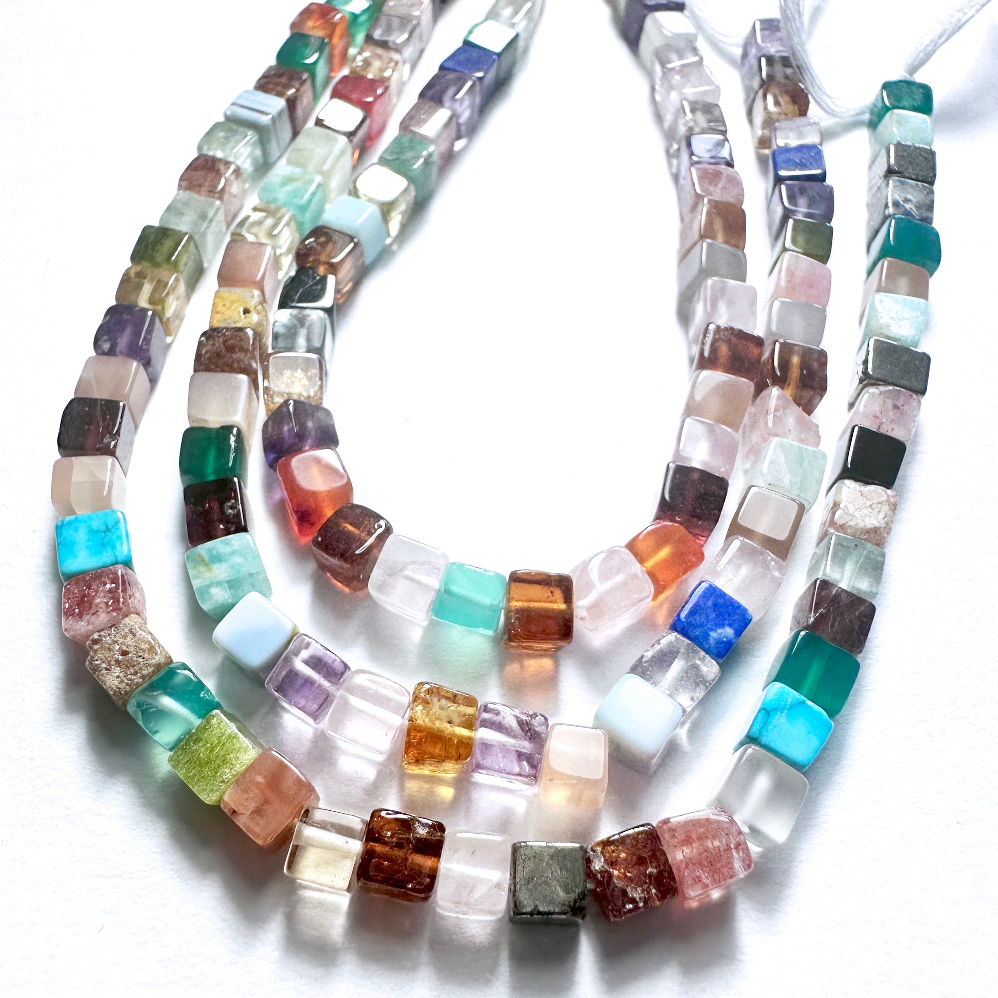 Delicate strands of Disco Smooth Square beads, showcasing their smooth design.