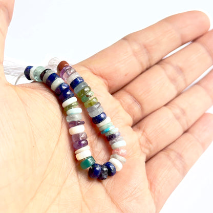 A person holds delicate strands of disco smooth wheel beads, showcasing their smooth design.