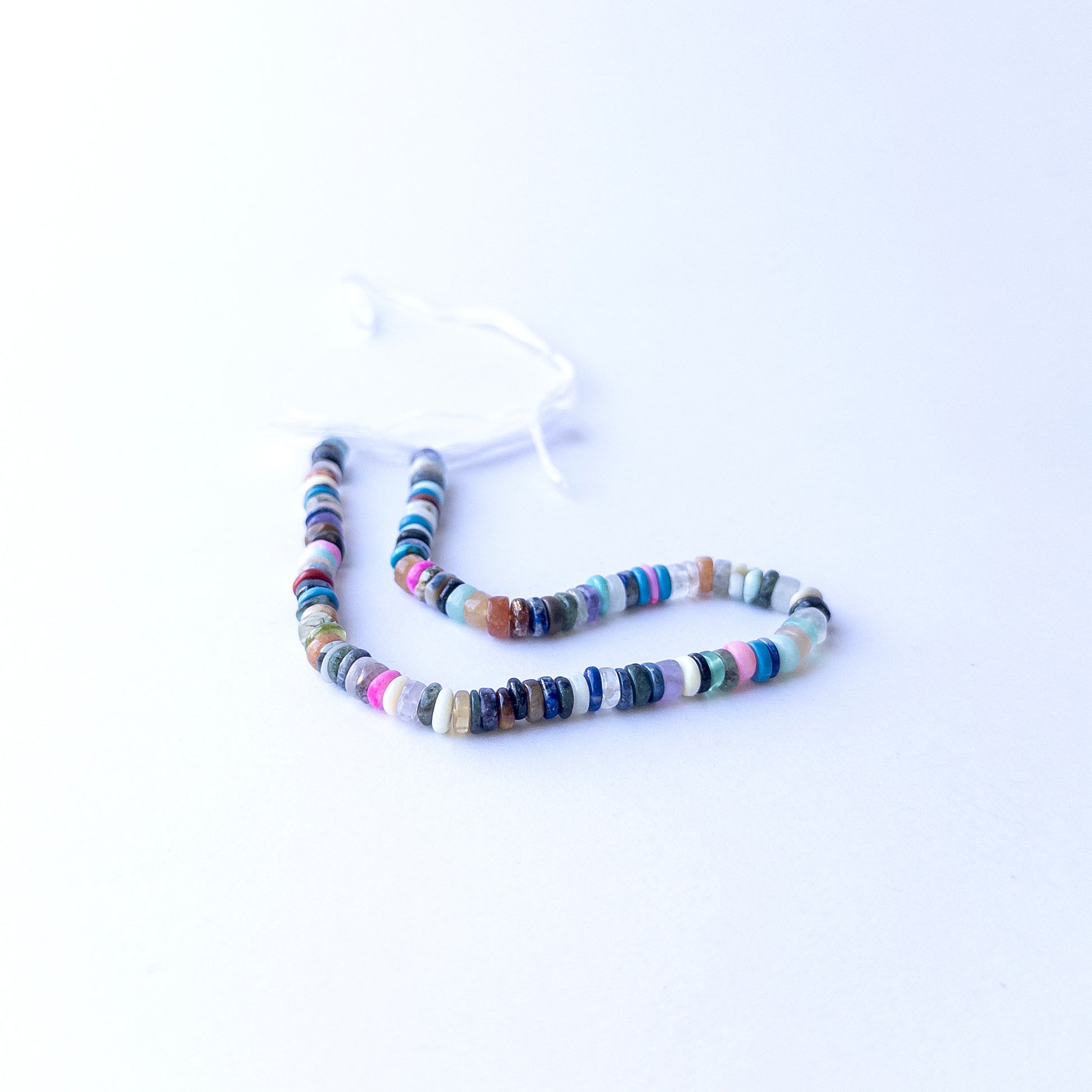 Disco smooth wheel heishi beads displayed in multiple strands, showing uniform 5mm sizing and vivid gemstone colours.
