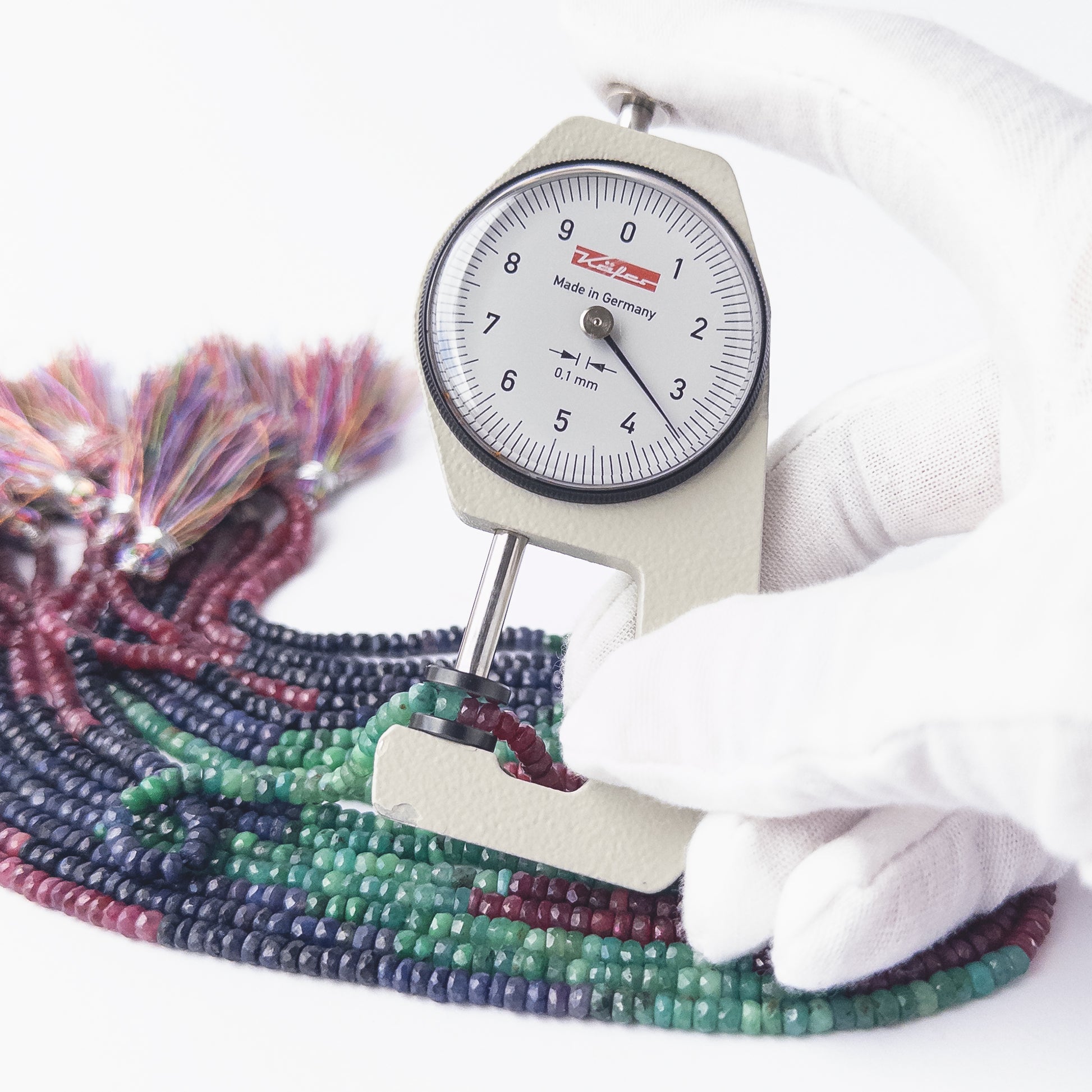 A dial gauge measures the Dyed Corundum faceted rondelle 3.7–5mm bead size gemstone.
