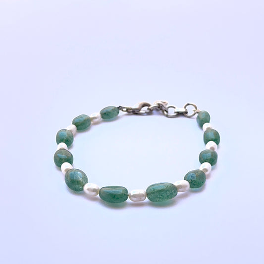 Close‑up of emerald and pearl beads arranged on a polished bracelet.
