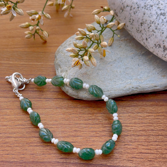Emerald and pearl bracelet featuring carved emerald beads and lustrous freshwater pearls.