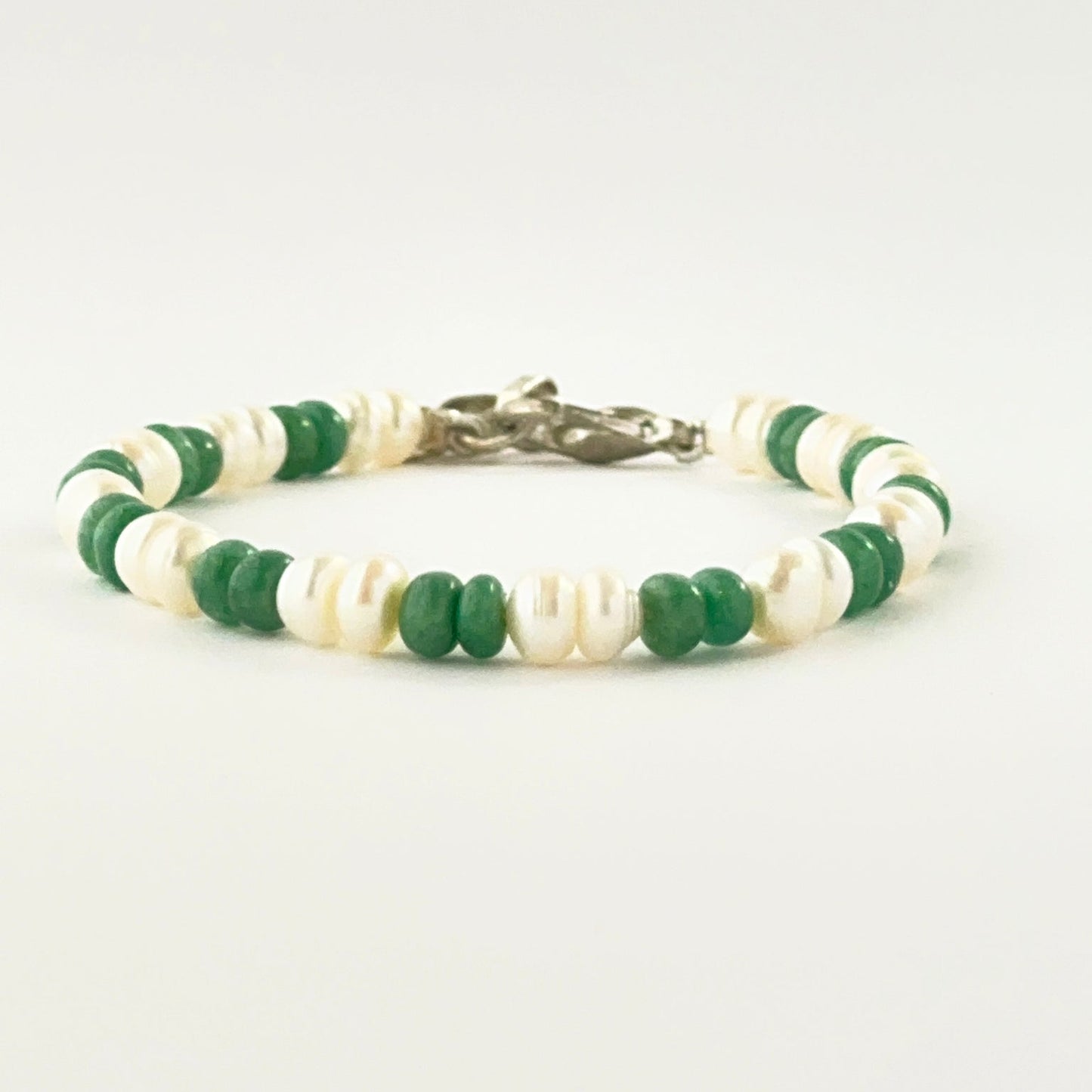 Smooth rondelle emerald and pearl bracelet arranged in a single adjustable strand.