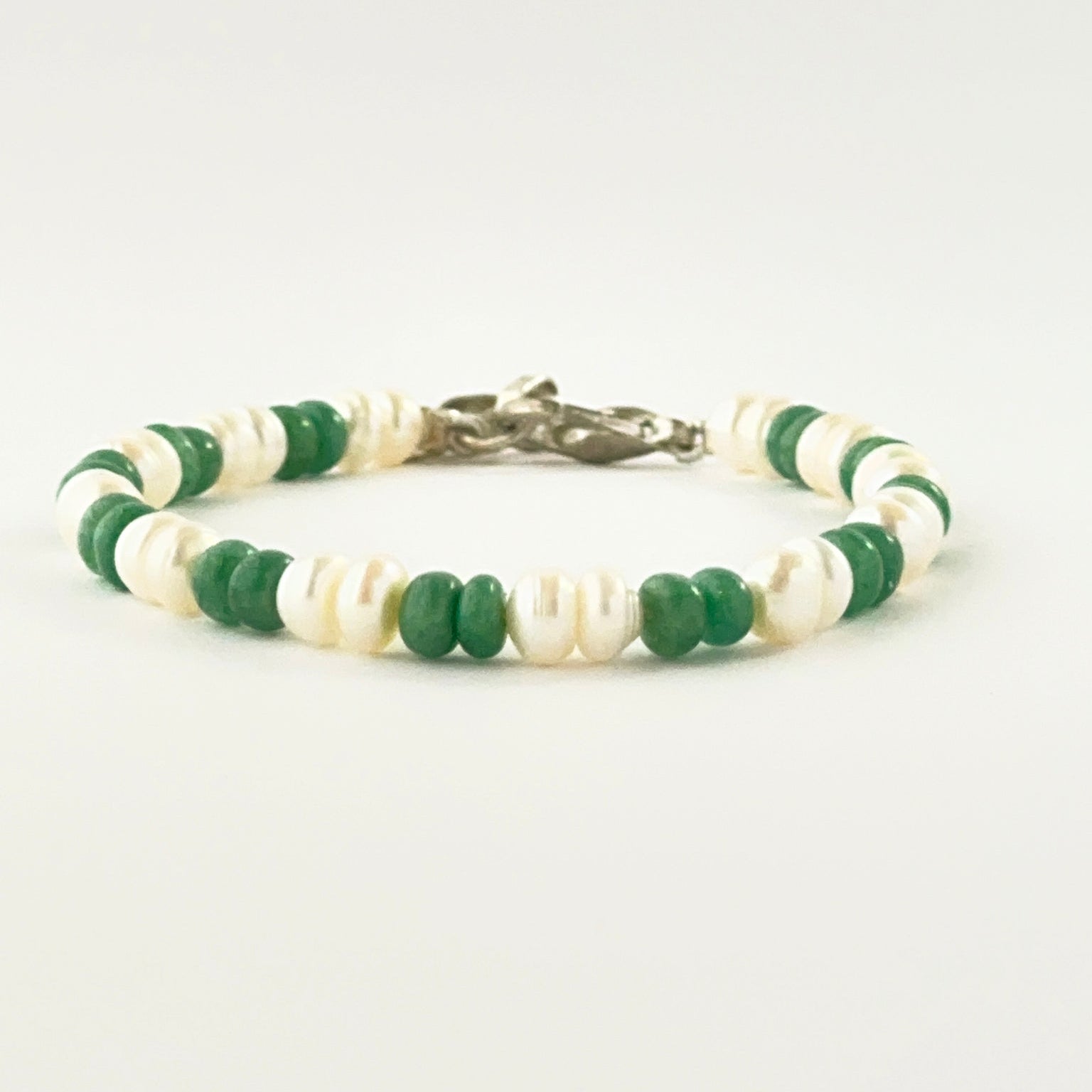 Smooth rondelle emerald and pearl bracelet arranged in a single adjustable strand.