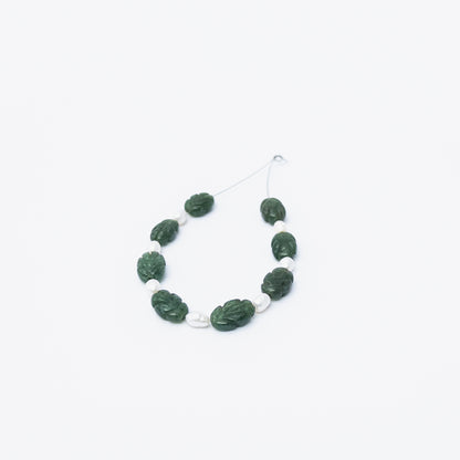 Emerald and Freshwater Pearl carved beads arranged together, showcasing rich green tones and soft pearly shine.