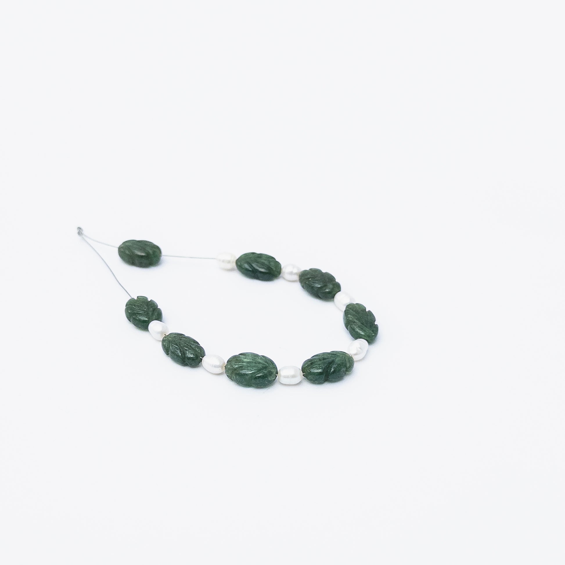 Close‑up of Emerald carved beads and Freshwater Pearls highlighting their polished texture and elegant mixed‑gem look.