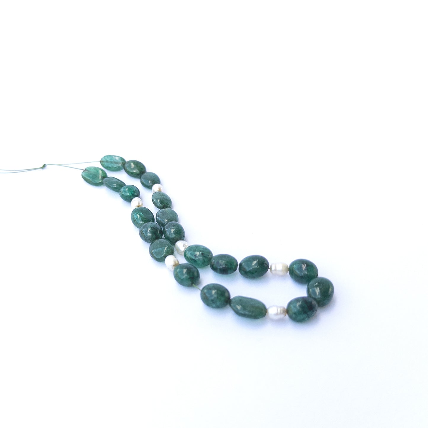 Emerald and freshwater pearl smooth oval beads arranged together showcasing natural green tones and soft pearl lustre for jewellery.