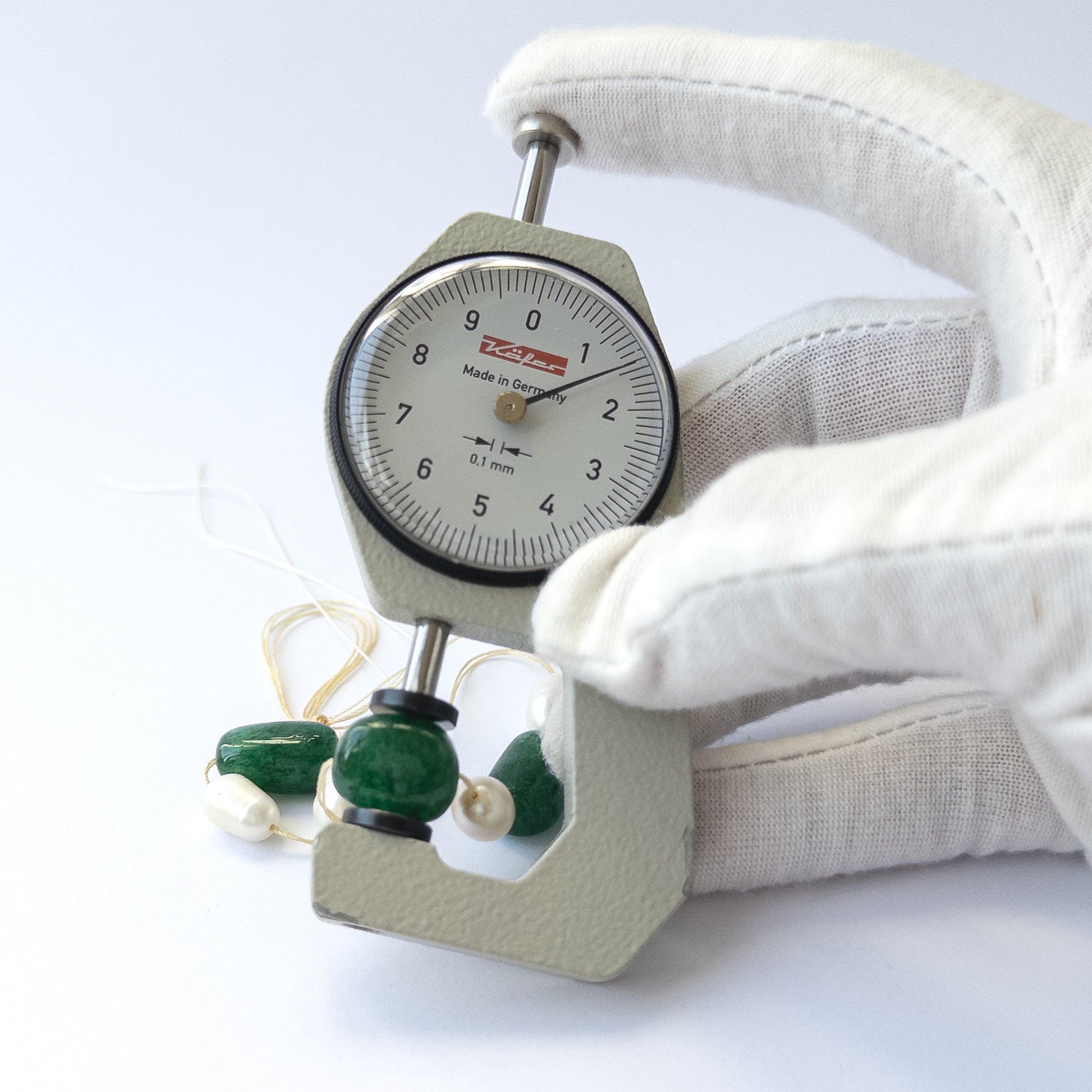 A dial gauge measures the Emerald and freshwater pearl smooth tumble 9.3–11.6mm gemstone.