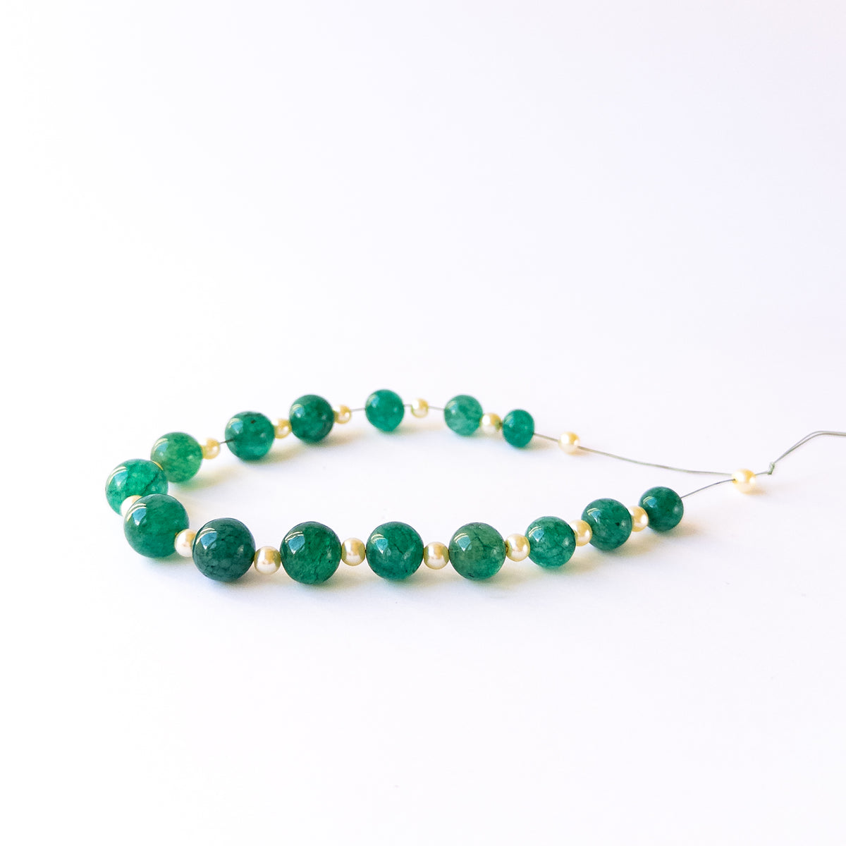 Genuine Emerald and Shell Pearl stone beads in smooth round cut arranged for DIY jewellery makers.