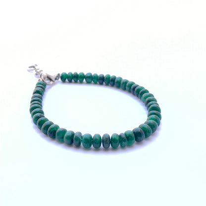 Close‑up of smooth emerald rondelle beads arranged on a polished bracelet.