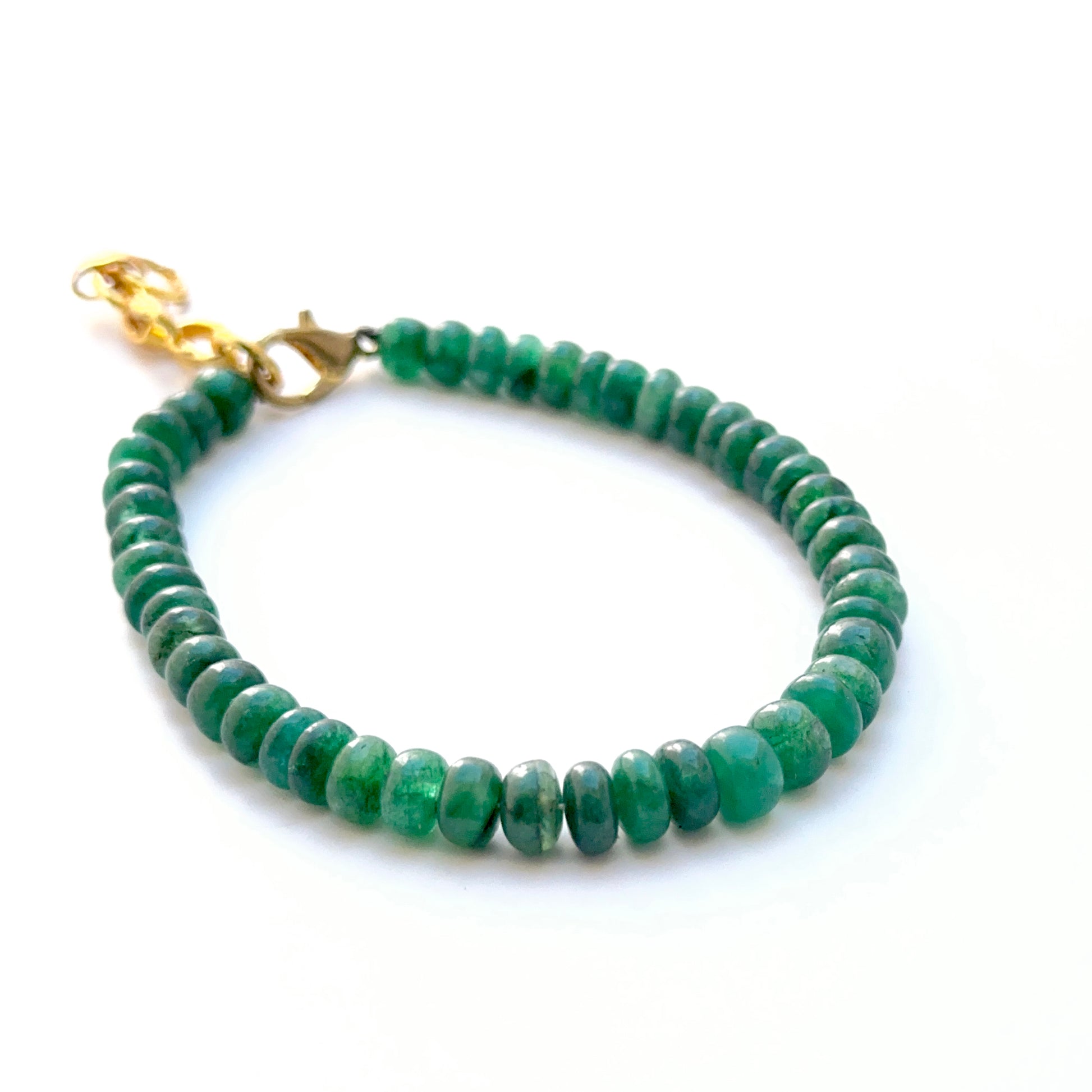 Close‑up of polished emerald rondelle beads arranged on a finished bracelet.