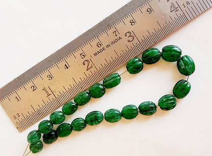 A ruler measures the emerald oval gemstone.