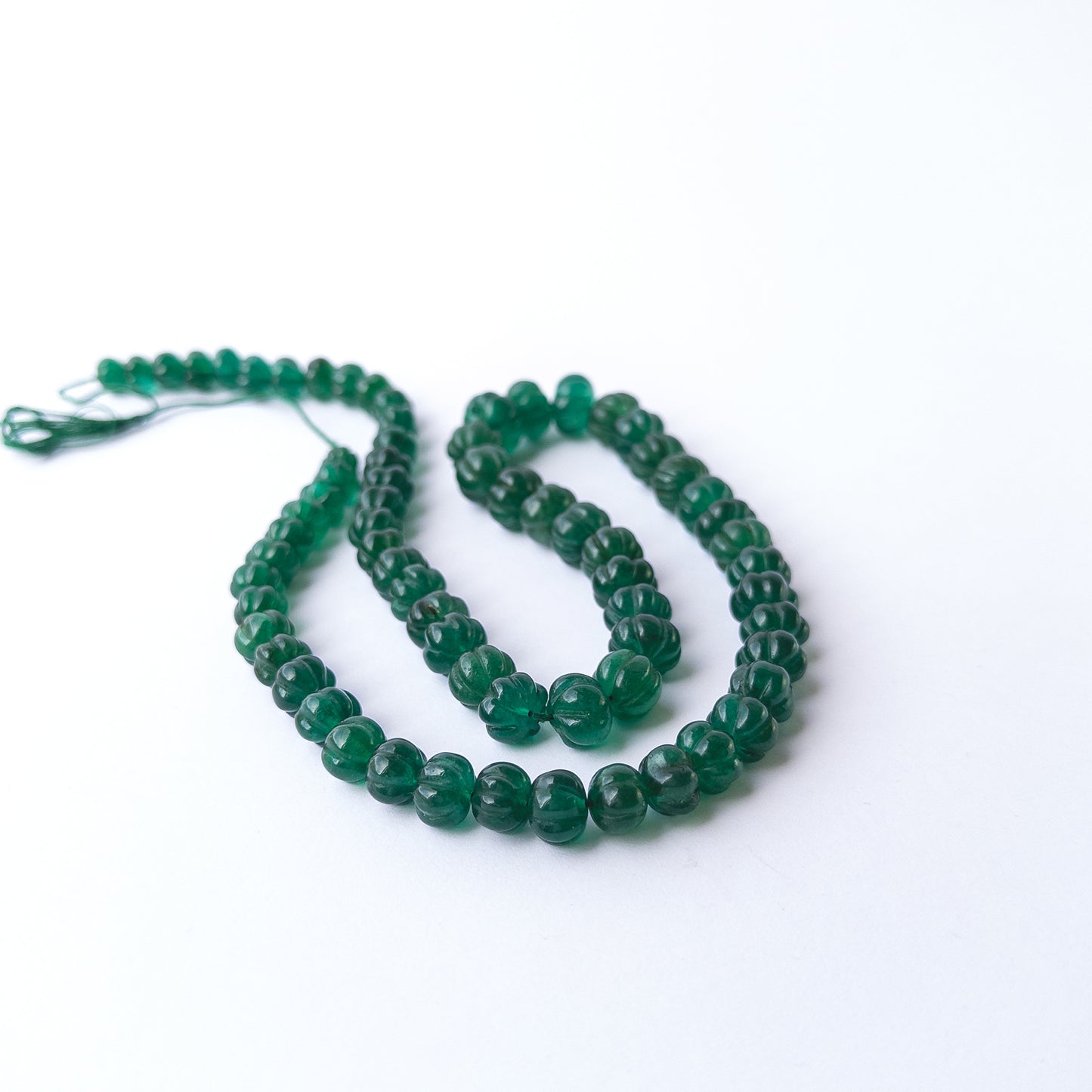 Vibrant green Emerald carved pumpkin beads arranged in a 53cm strand for handmade gemstone jewellery making.