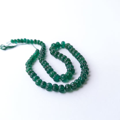 Vibrant green Emerald carved pumpkin beads arranged in a 53cm strand for handmade gemstone jewellery making.