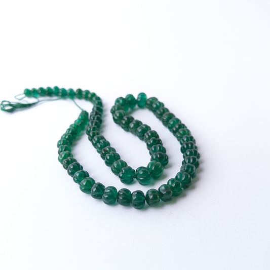 Vibrant green Emerald carved pumpkin beads arranged in a 53cm strand for handmade gemstone jewellery making.
