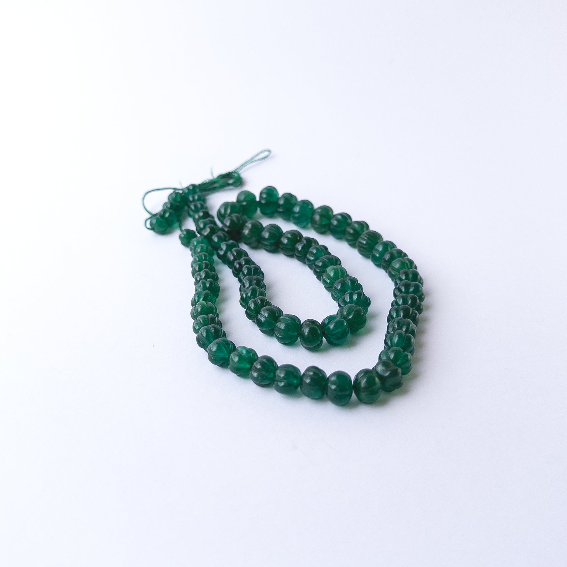 Authentic Emerald stone beads showcasing rich colour and carved pumpkin texture for jewellery designers.