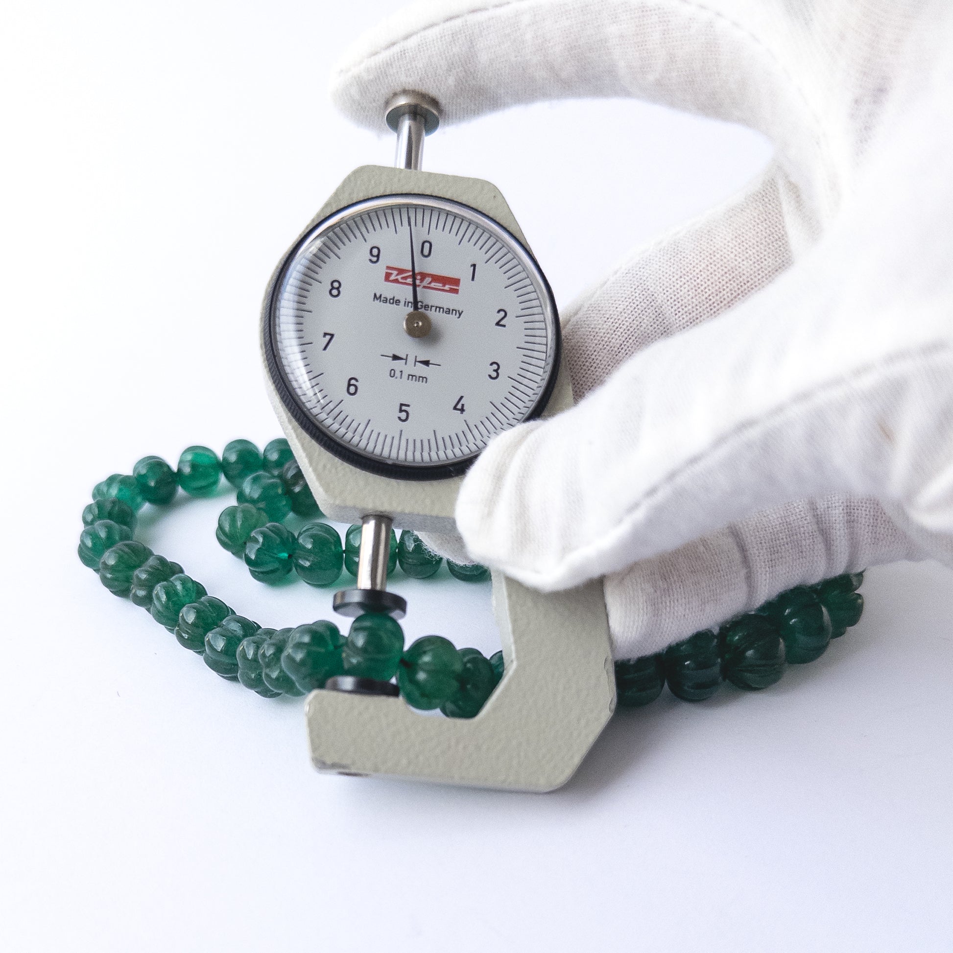 A dial gauge measures the Emerald carved pumpkin 7.5–12.5mm gemstone.