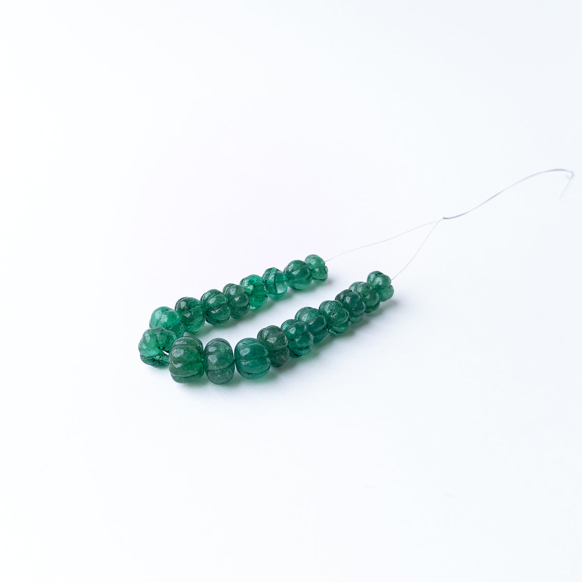 Emerald carved pumpkin gemstone beads showcasing vibrant green hues with detailed carving and exceptional gemstone character.