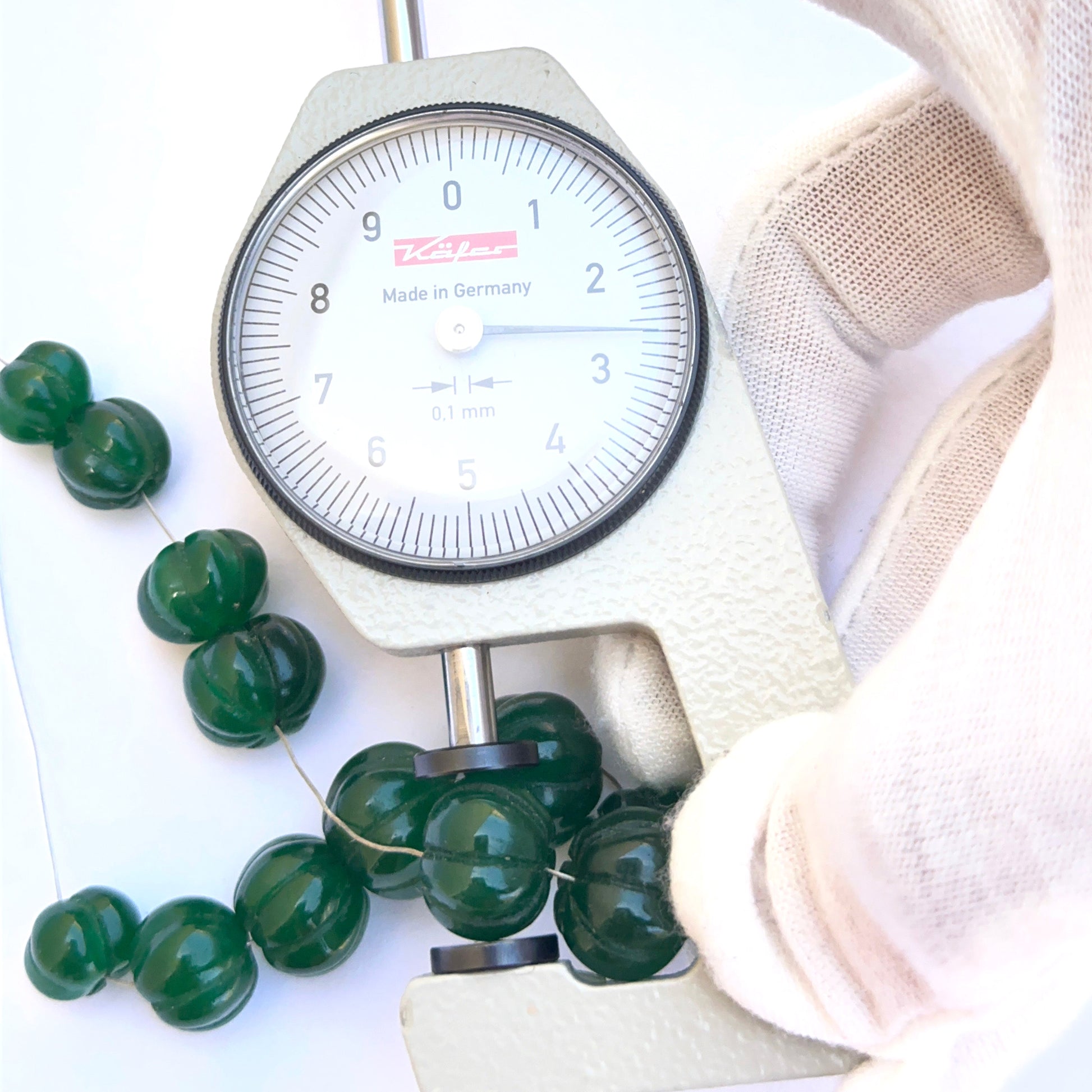 A dial gauge measures the emerald carved pumpkin 9.6–14mm gemstone.