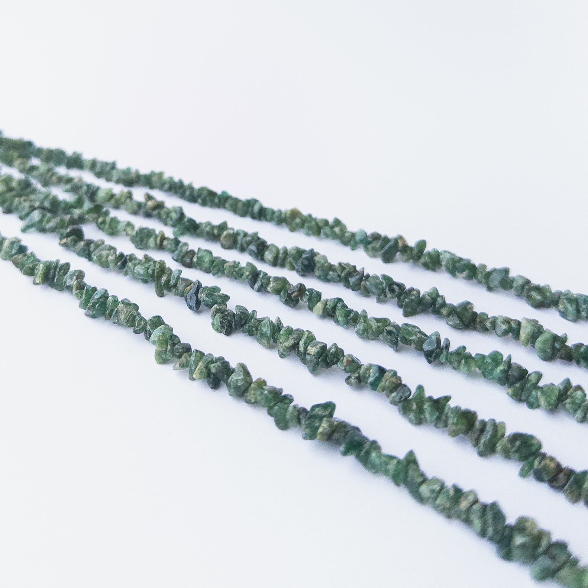 Handmade jewellery components featuring smooth Shaded Emerald chip beads in a neatly arranged strand.