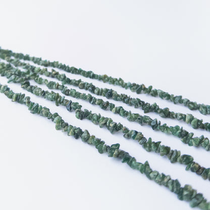 Handmade jewellery components featuring smooth Shaded Emerald chip beads in a neatly arranged strand.