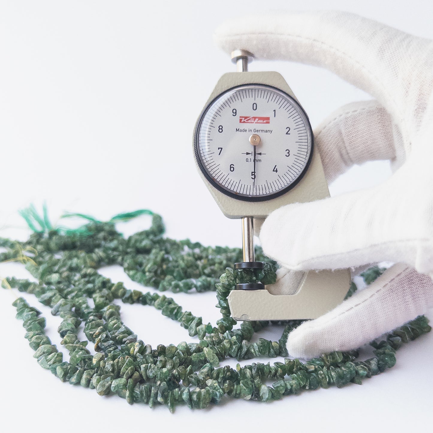 A dial gauge measures the Shaded Emerald chip 4.5–5mm gemstone.