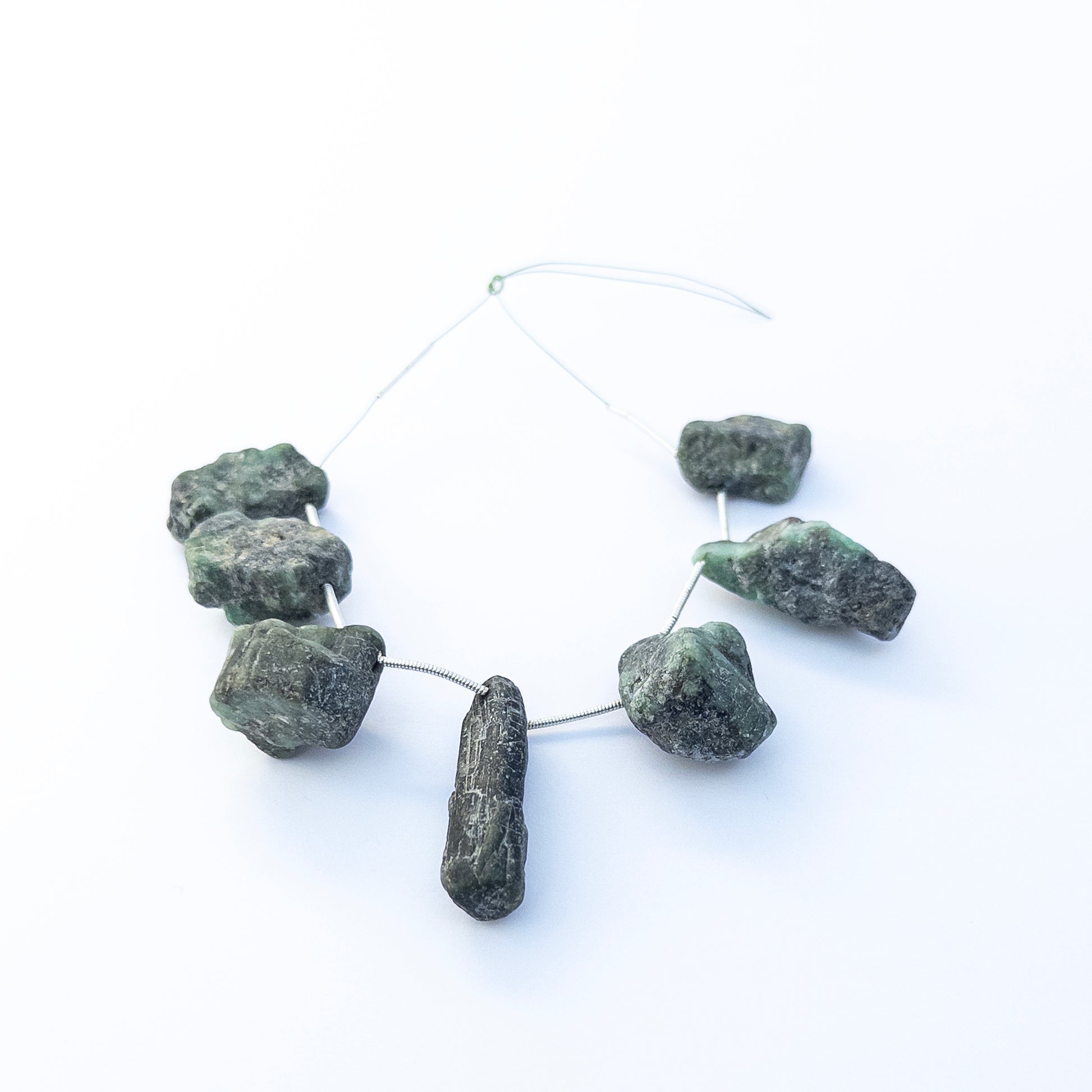 Close‑up of Emerald drilled rough gemstones highlighting their natural texture, raw edges and rich green hues.