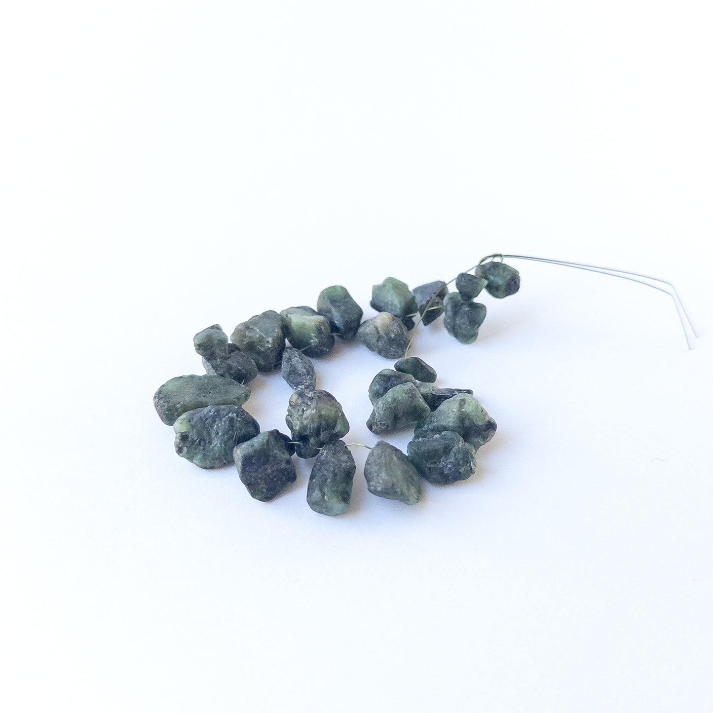 Authentic Emerald rough beads with organic texture arranged in a 21‑piece set for DIY jewellery creators.