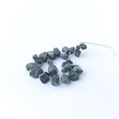 Authentic Emerald rough beads with organic texture arranged in a 21‑piece set for DIY jewellery creators.
