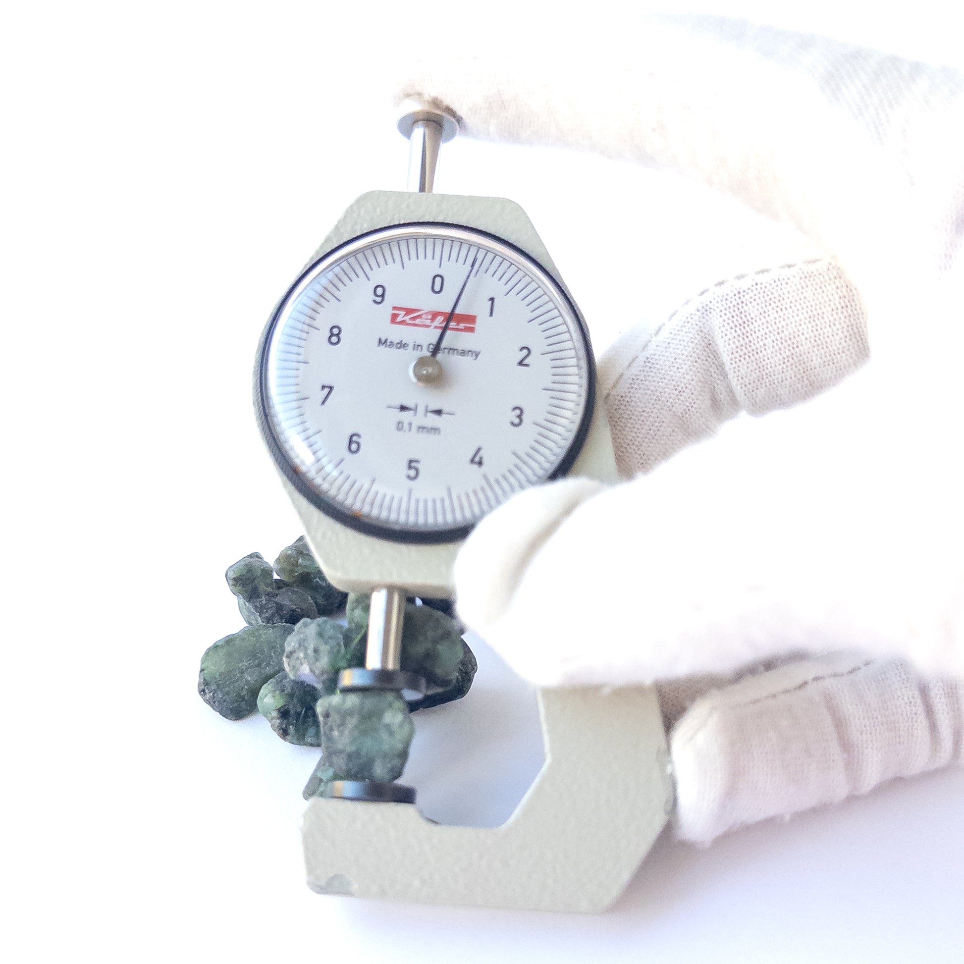 A dial gauge measures the Emerald drilled rough 8.5–11.5mm gemstone.