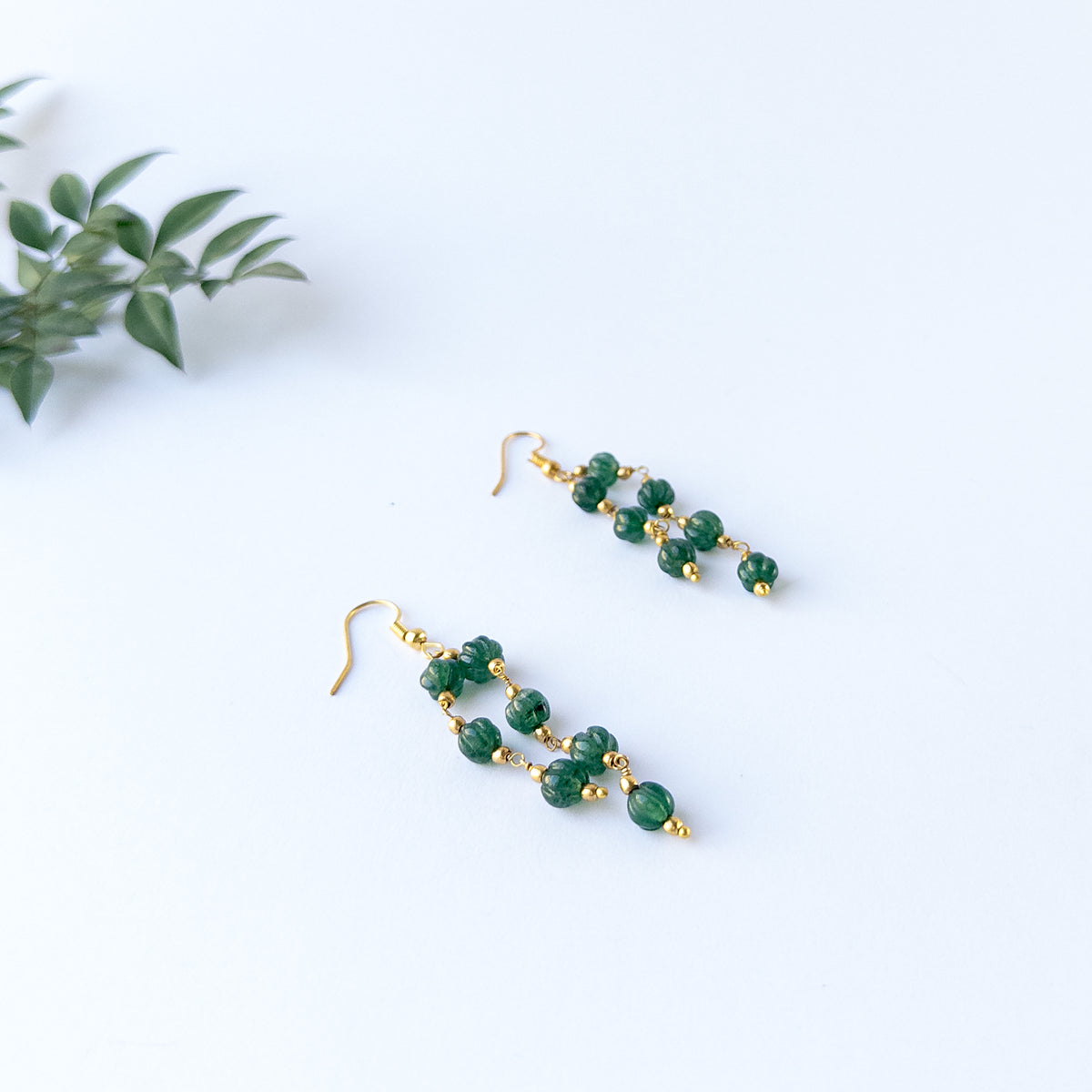 Emerald gemstone necklace and earrings displaying carved detailing, and premium necklace.