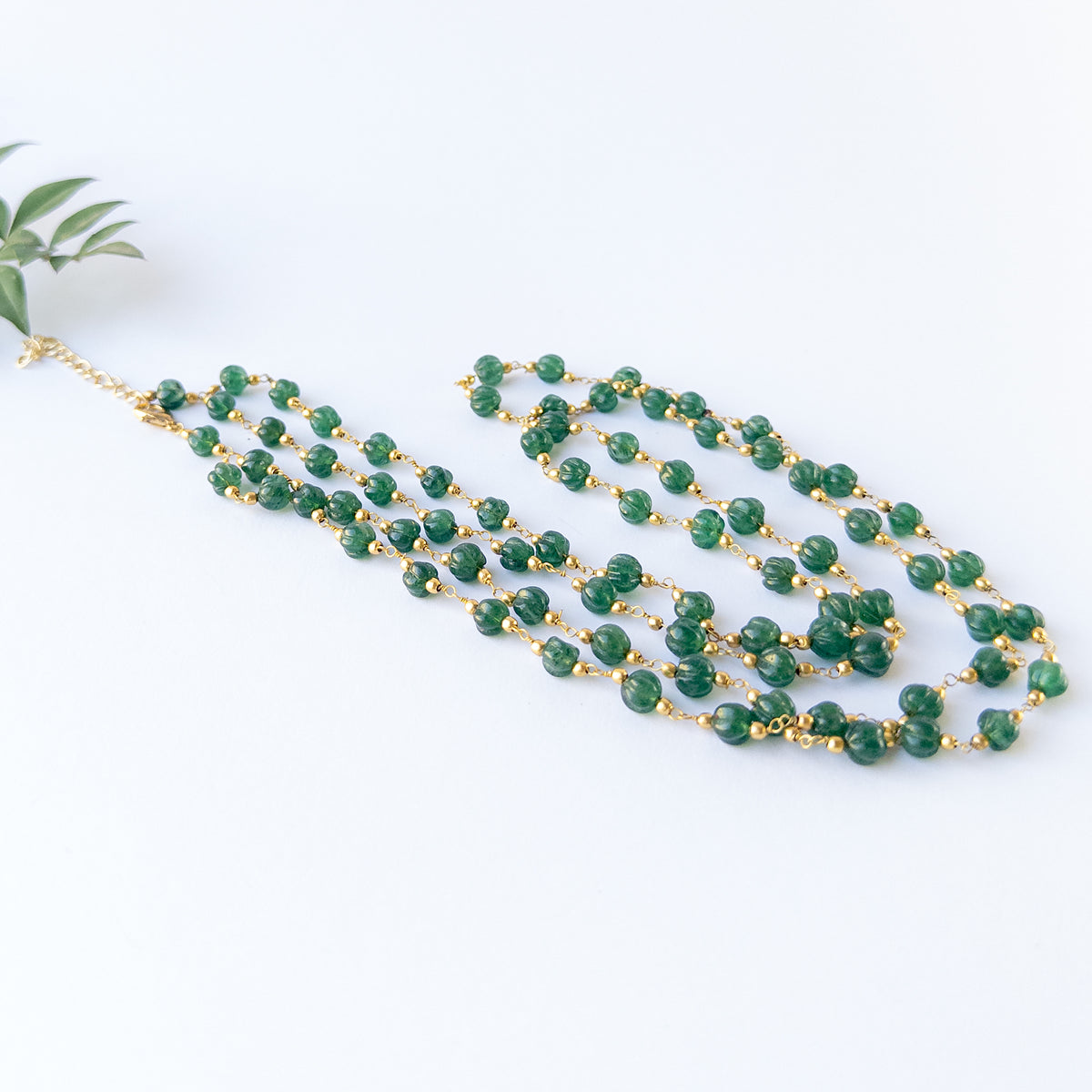 Emerald pumpkin‑cut beads 5.5–6mm showing rich green colour and carved shine in a 2‑strand necklace set.