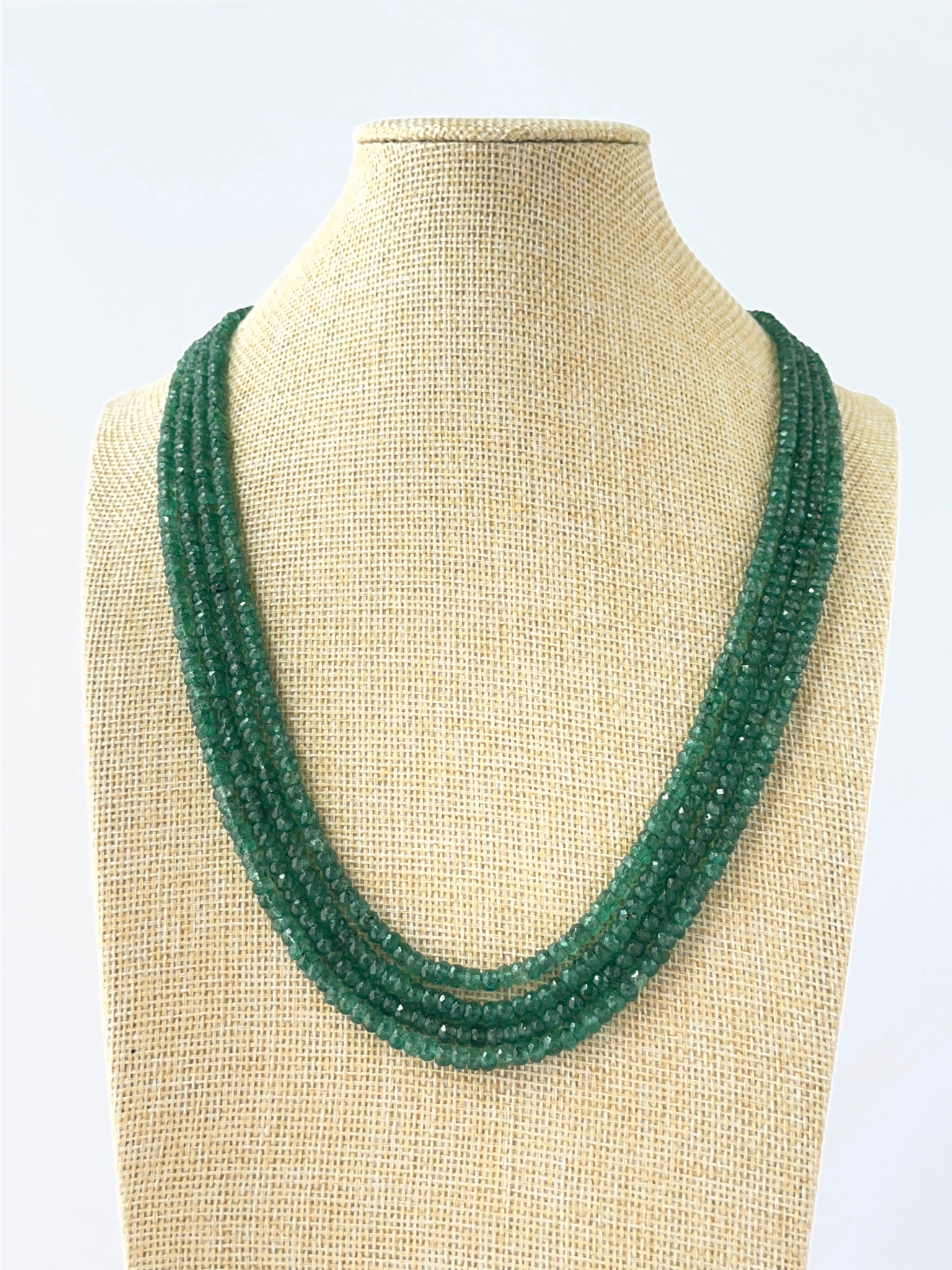 Four‑strand emerald necklace featuring faceted rondelle beads sized 4–4.6mm in layered adjustable lengths.