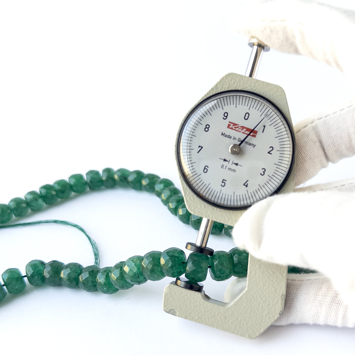 A dial gauge measures the Emerald faceted rondelle 9–11.5mm gemstone.