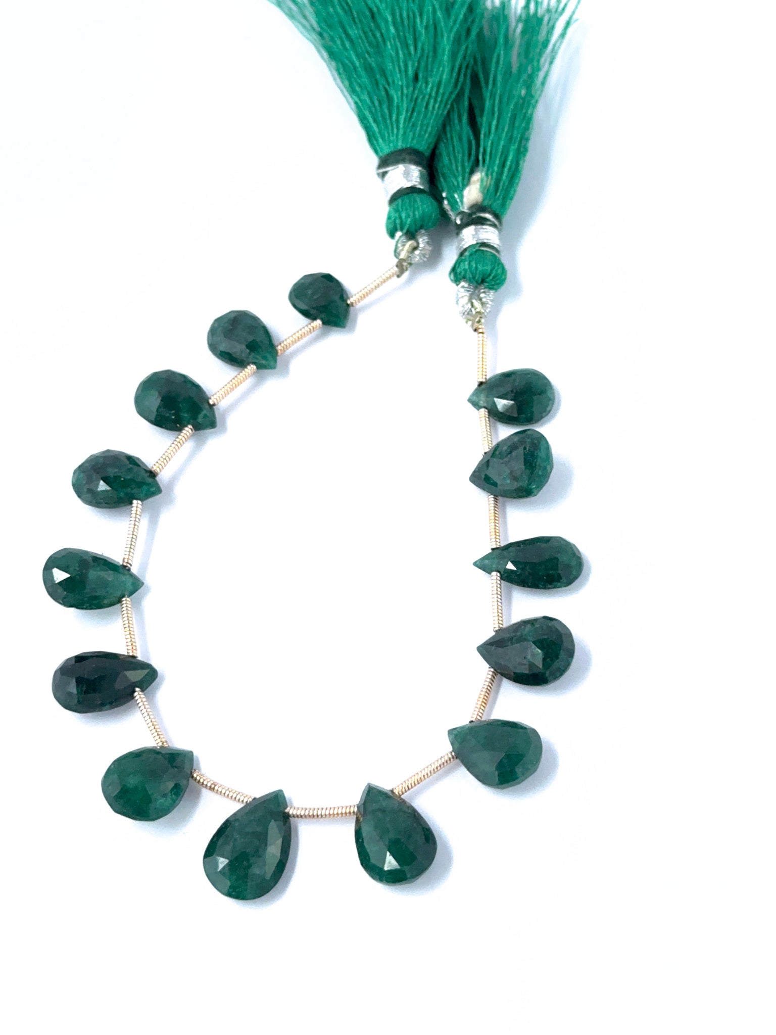 Emerald faceted teardrops showing vivid green colour and sparkling gemstone cuts.