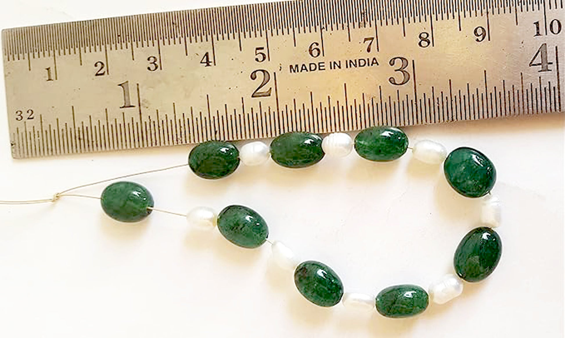 A rulers measures the emerald oval gemstone.