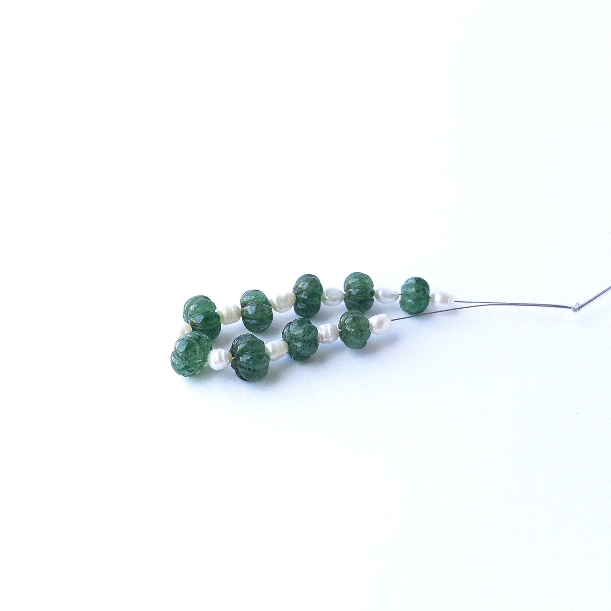 Authentic emerald and freshwater pearl beads showcasing rich green tones and lustrous white accents.