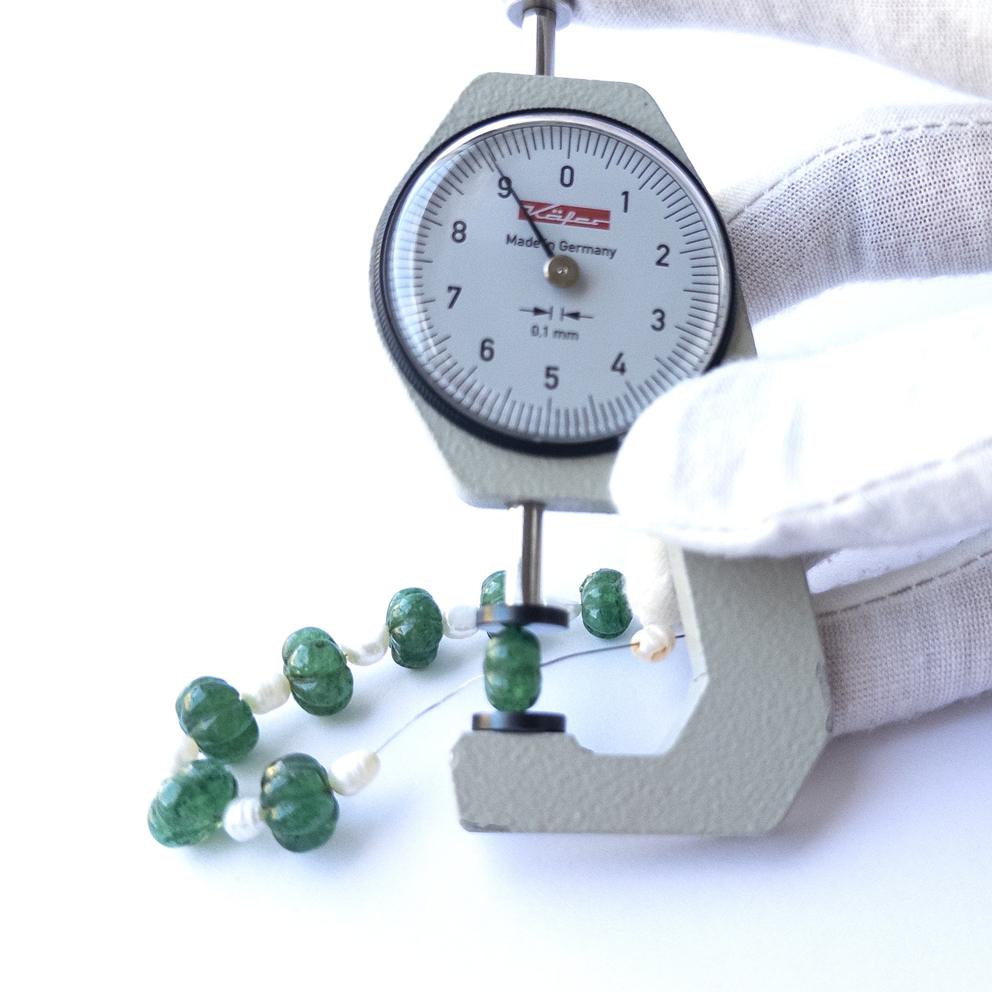 A dial gauge measures the Emerald and Freshwater Pearl pumpkin‑cut 8–10.3mm gemstone.