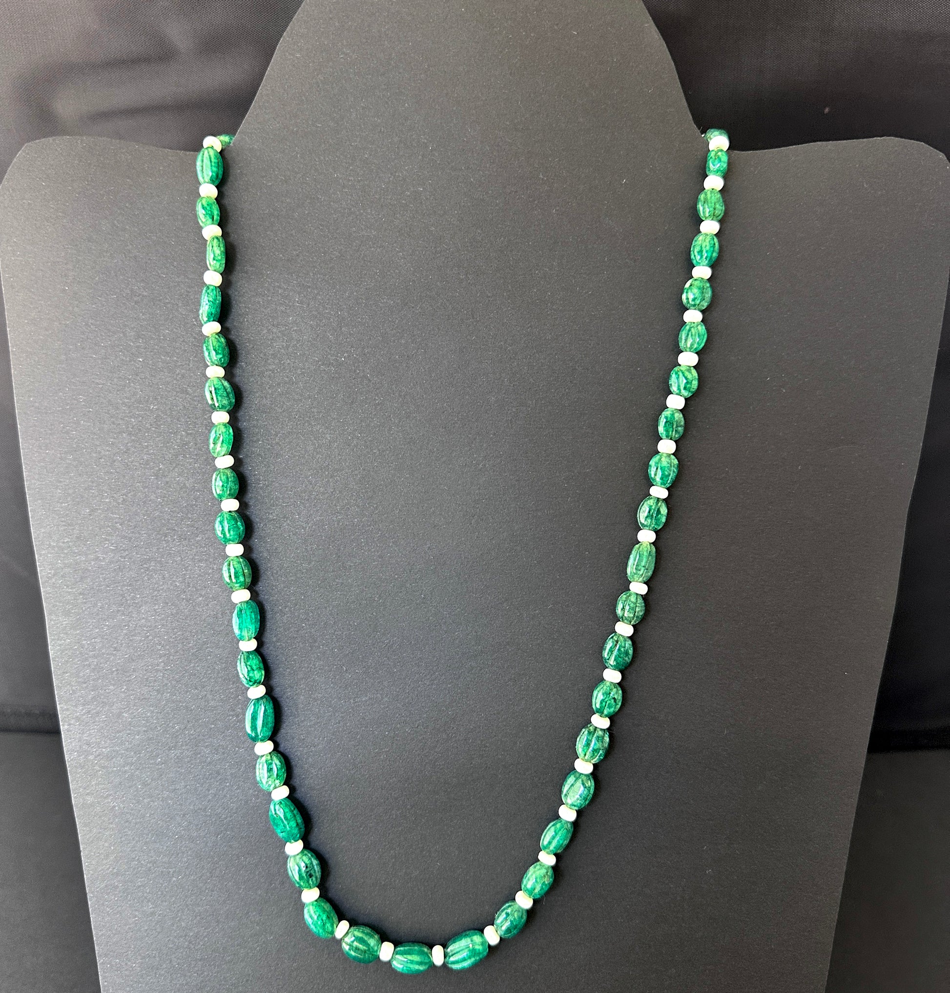 Close-up of carved oval emerald beads, 145 carats, highlighting clarity, polish, and natural gemstone brilliance.