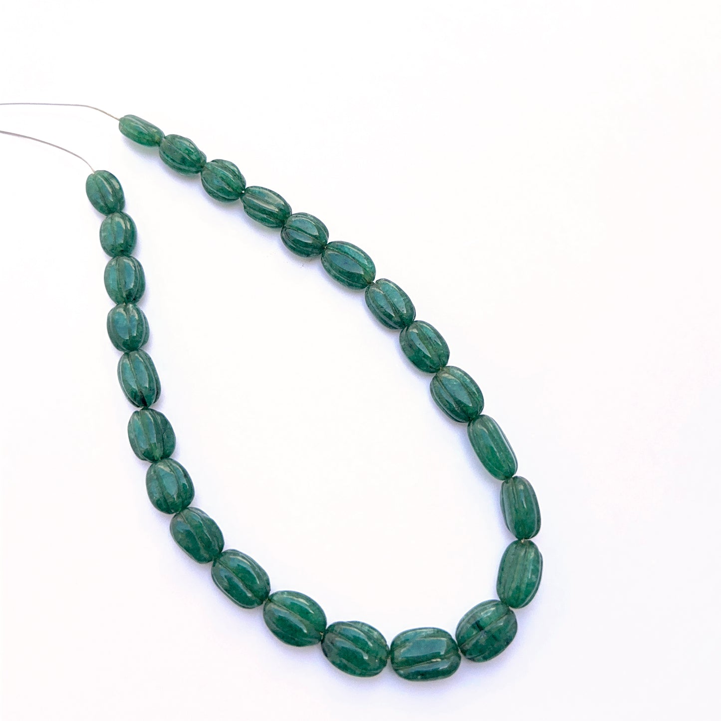 Emerald necklace with carved oval beads showing rich colour and handcrafted detailing.