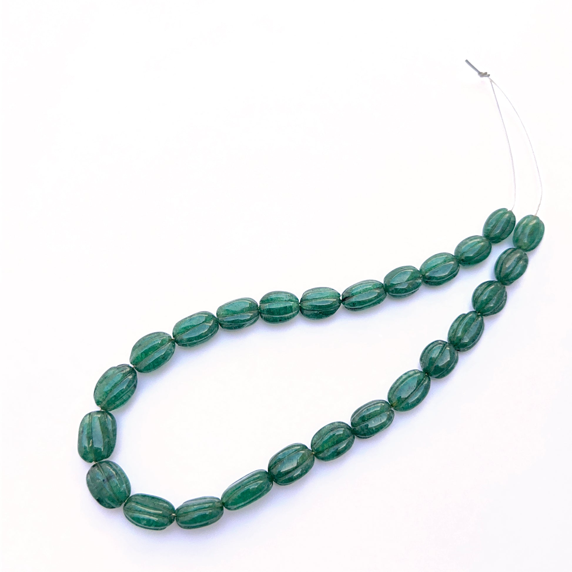 Emerald necklace featuring carved oval emerald beads with deep green tones and polished detail.