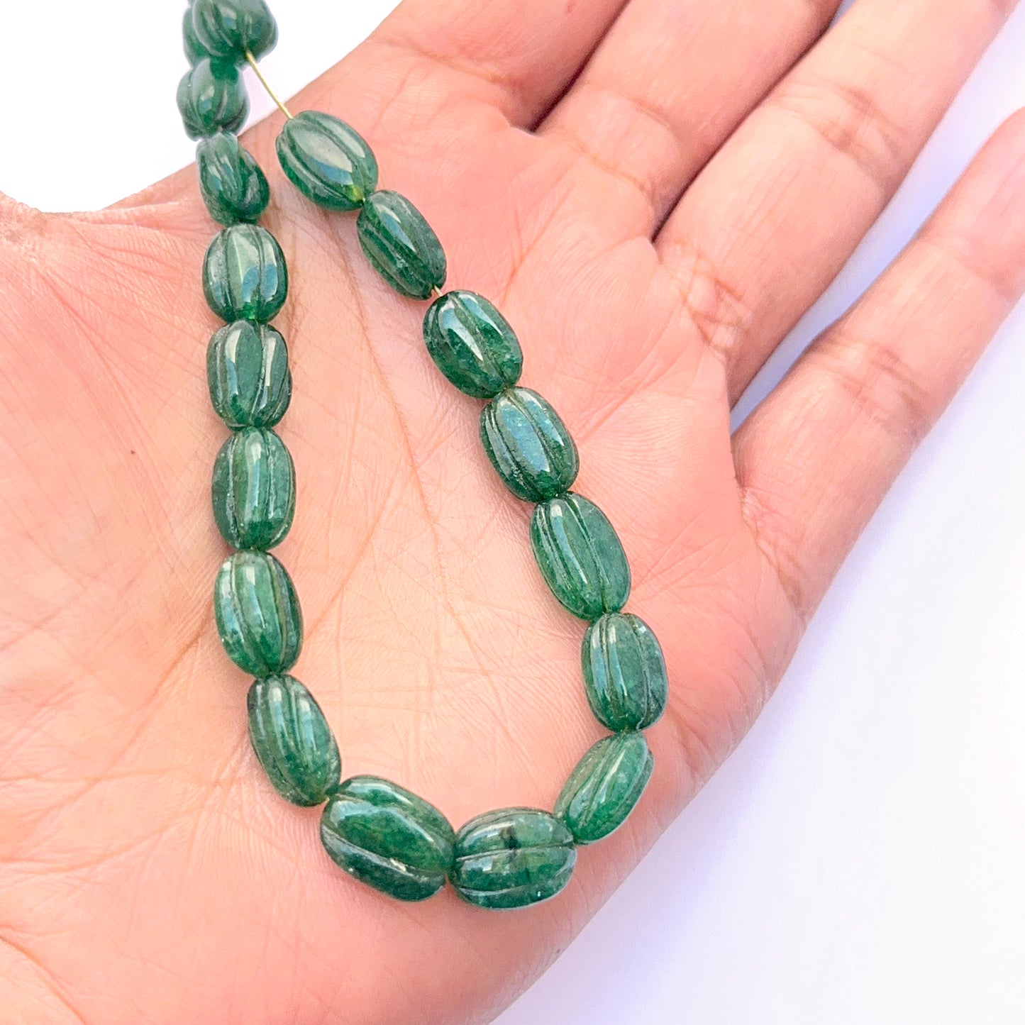 Emerald necklace featuring carved beads with smooth polish and elegant shape.