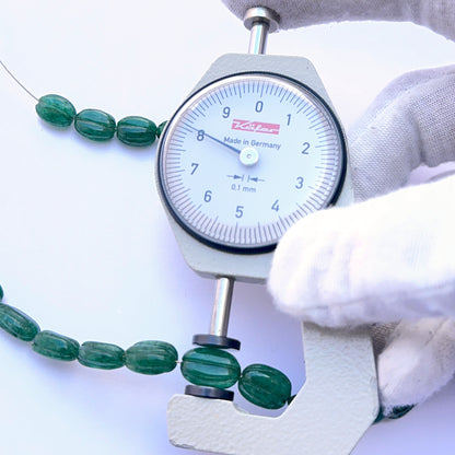A dial gauge measures the emerald carved oval 7.4–8.5mm gemstone.
