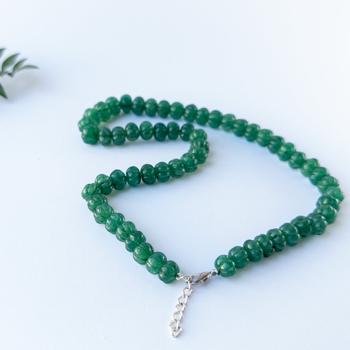 Genuine gemstone beads in Emerald showing carved brilliance and quality craftsmanship in a necklace design.