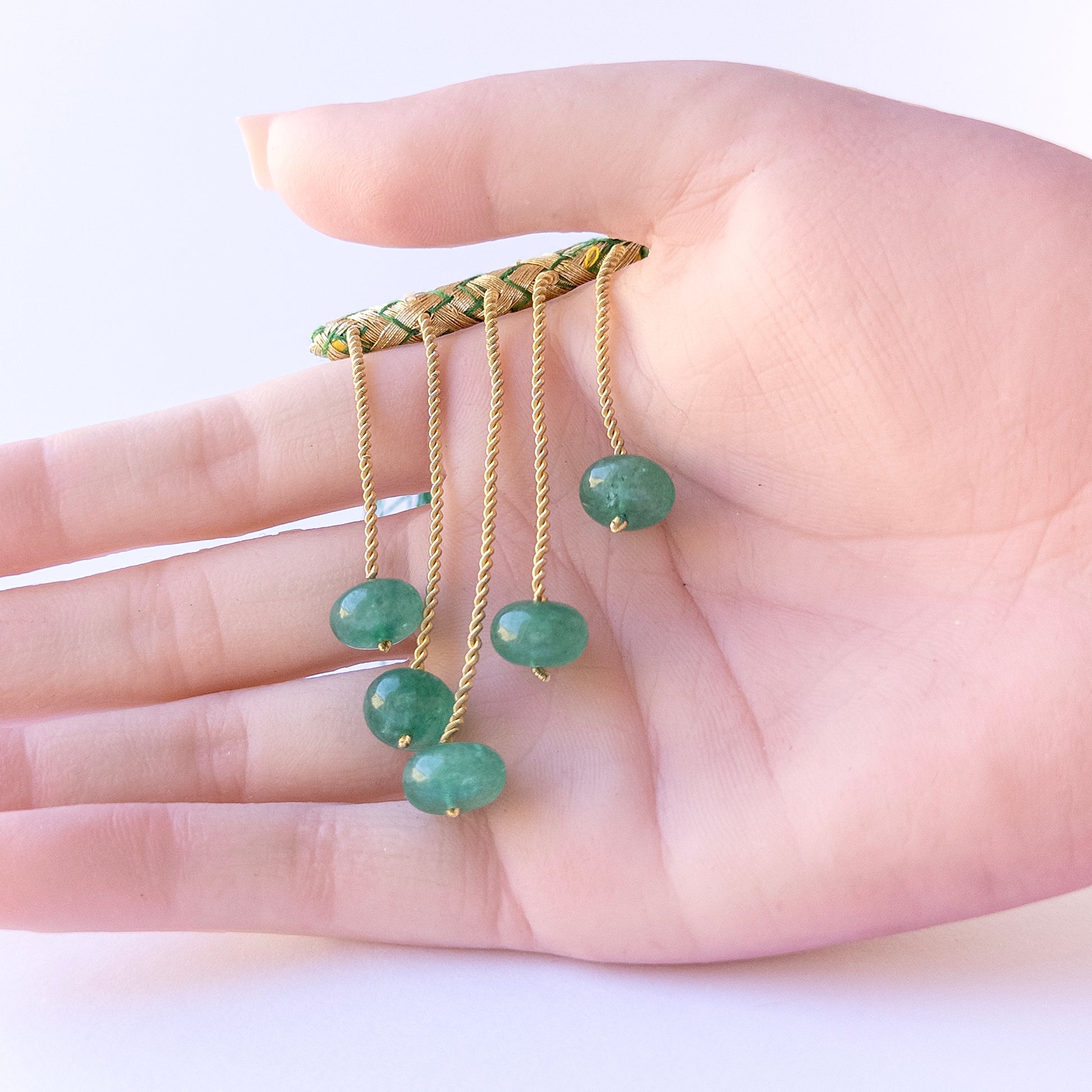 A person holds delicate pieces of Emerald beads, showcasing their Smooth Rondelle design.