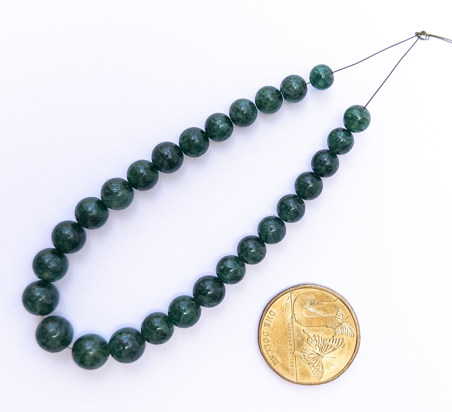 Polished Emerald round beads showing vibrant green hues and refined shaping.